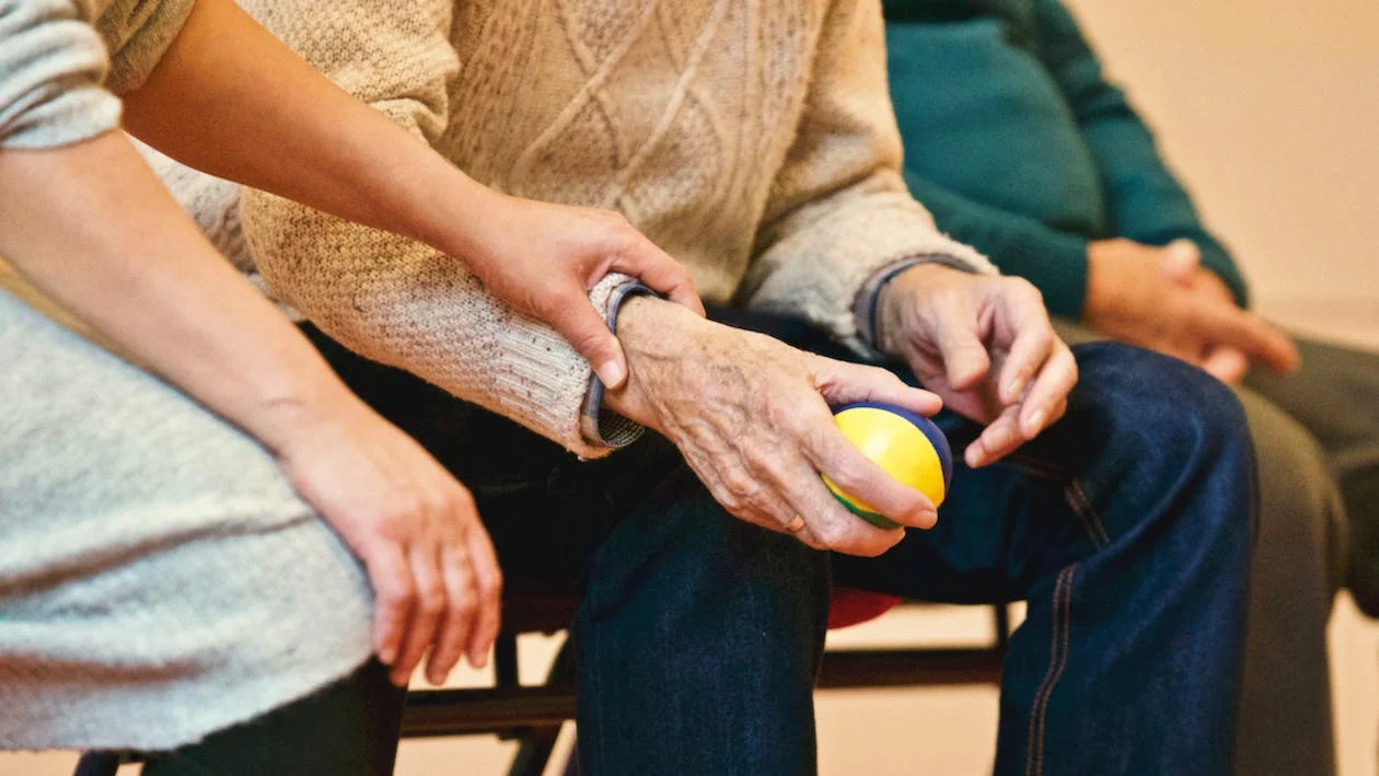 Younger person holding the arm of an older gentleman, who is holding a coloured ball.