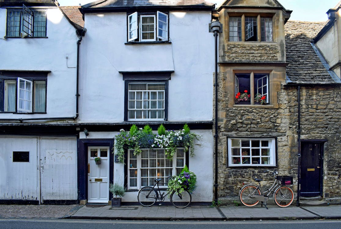 A mid-terrace house with open upstairs windows and a bicycle parked outside.