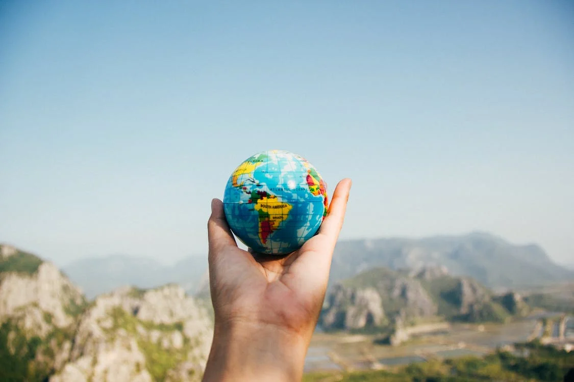 A hand holding a small globe.