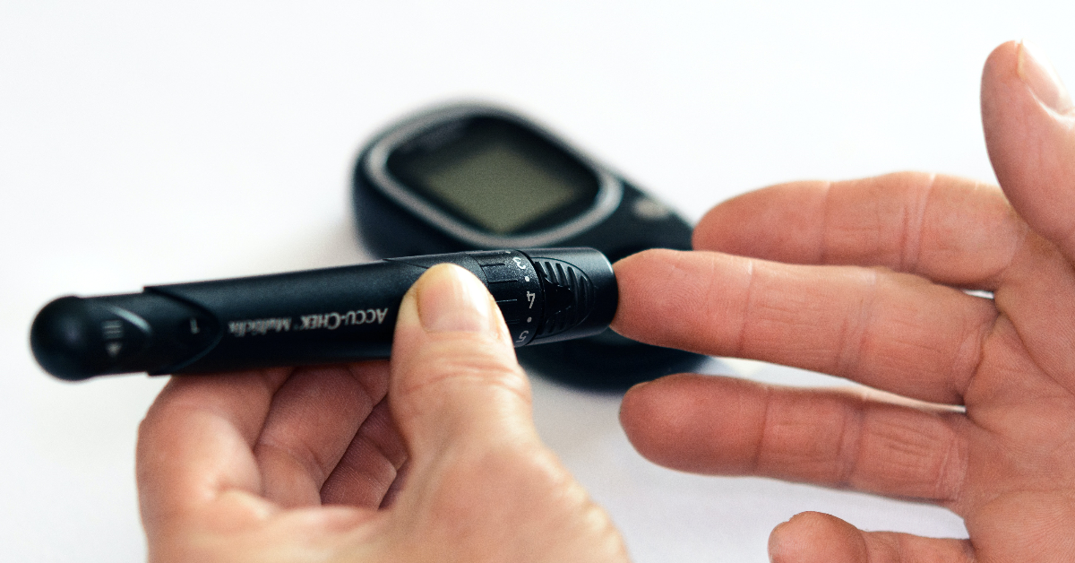 A person's hands, showing a glucose finger-prick test being performed.