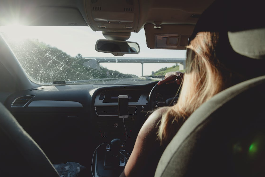 A woman driving on a motorway, pictured from the back seat.