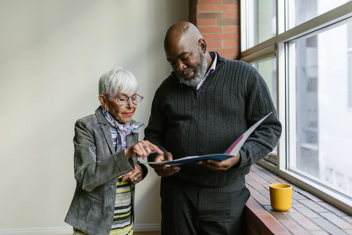 Two elderly people looking at papers inside a folder.