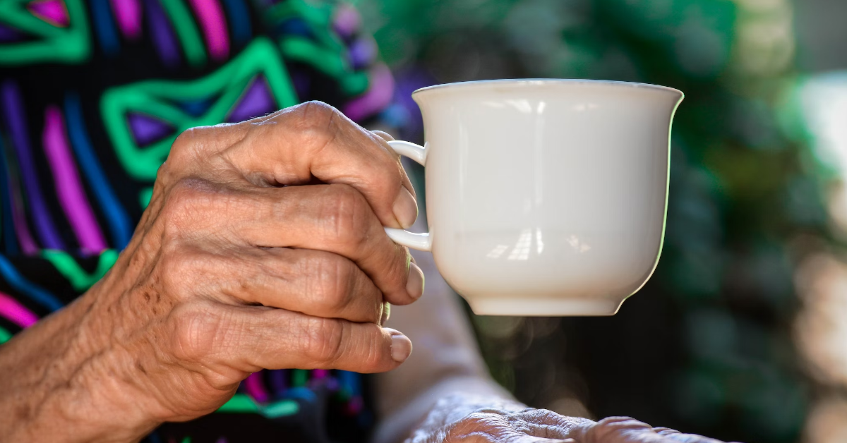 An older lady's hand holding a cup.