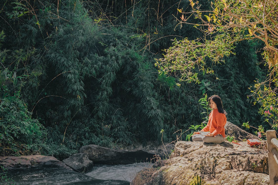 Woman striking a yoga pose in a forest.