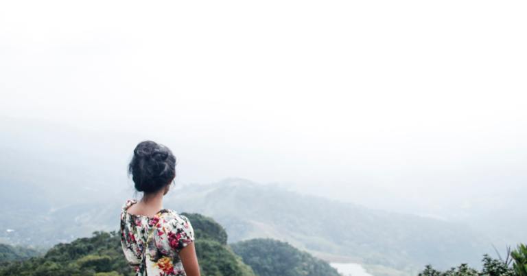 A woman standing on her own, looking into the distance across hilltops.