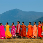 A group of women in colourful dress, with a backdrop of mountains.