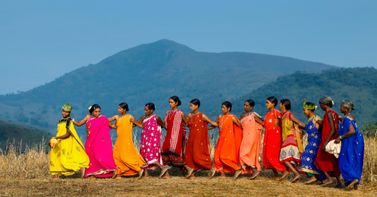 A group of women in colourful dress, with a backdrop of mountains.