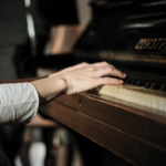 A hand placed on the keys of a piano.